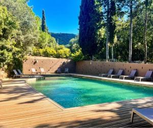 a swimming pool with chairs and a wooden deck at Cottage PARKS OLVA in Sartène