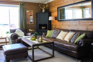 a living room with a leather couch and a table at Grønebakkins smørøye in Beitostøl