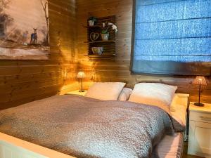a bedroom with wooden walls and a bed with two lamps at Grønebakkins smørøye in Beitostøl