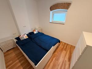a bedroom with a bed with blue sheets and a window at Donau Apartment in Sinzing