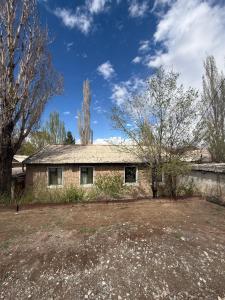 an old brick house with trees in the yard at Nooruz hotel in Naryn