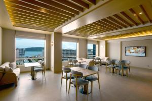 a waiting room with tables and chairs and windows at Cititel Express Kota Kinabalu in Kota Kinabalu