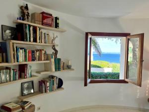 a room with bookshelves and a window with a view of the ocean at Villa Sa Torre Blanca in Colonia de Sant Pere
