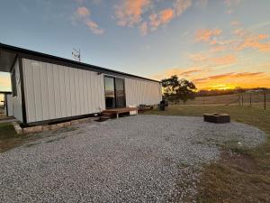 a building with a bench next to a field at Peaceful Farm Retreat - Luxury Cabins in Goulburn in Norwood