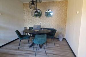 a dining room table with chairs and a laptop on it at Nes-Tijd in Nes