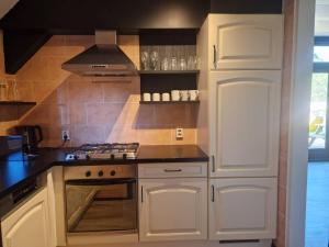 a kitchen with white cabinets and a stove top oven at Nes-Tijd in Nes