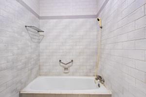 a white bathroom with a tub and a shower at OYO 3934 Hotel Istana in Pekalongan