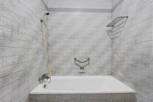 a bath tub with a hose in a bathroom at OYO 3934 Hotel Istana in Pekalongan