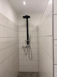 a shower with a hose in a white tiled bathroom at Ferienwohnung "Zum Pfadfinder" in Thalfang +17 photos