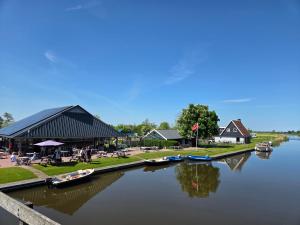 a river with boats docked next to a building at Tsjirk in Sprong +6 photos