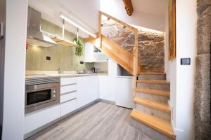 a kitchen with white cabinets and a wooden staircase at Villa Santa Bárbara in Vila Nova de Gaia