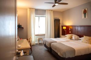 a hotel room with two beds and a desk at Hotel Les Almadies - Coeur de Ville in Saint-Jean-de-Luz