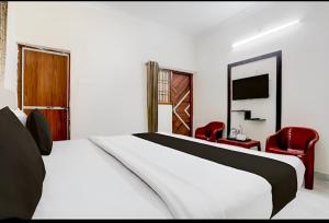 a bedroom with a white bed and a red chair at Grand Ayushmaan - Best Hotel in Jabalpur in Jabalpur