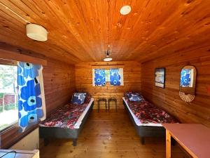 a room with three beds in a wooden room at Kyyjärvi Camping And Hotels Oy in Kotkaniemi