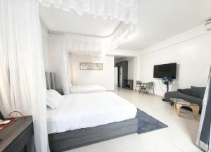 a white bedroom with a bed and a tv at Ucha Hotel & Suites in Kampala +38 photos