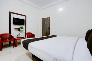 a bedroom with a bed and two red chairs at Grand Ayushmaan - Best Hotel in Jabalpur in Jabalpur