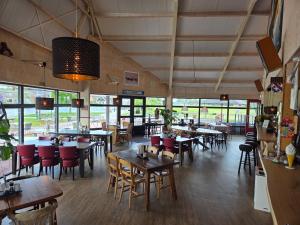 a restaurant with tables and chairs and windows at Tsjirk in Sprong