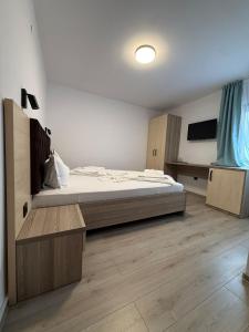 a bedroom with a large bed and wooden floors at Pensiunea Miruna Valentin in Jupiter