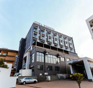 a building with a car parked in front of it at Ucha Hotel & Suites in Kampala