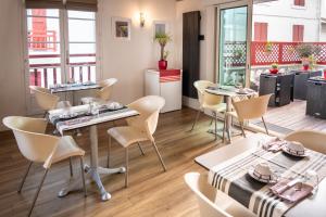 a restaurant with tables and chairs in a room at Hotel Les Almadies - Coeur de Ville in Saint-Jean-de-Luz