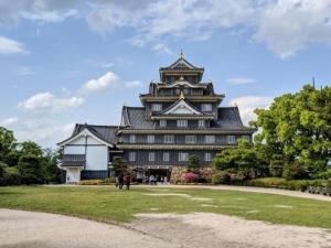 a large building with a tower on top of a park at Okayama International Hotel in Okayama