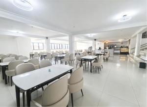 a dining room with tables and white chairs at Ucha Hotel & Suites in Kampala