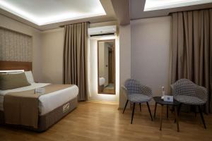 ein Schlafzimmer mit einem Bett, zwei Stühlen und einem Spiegel in der Unterkunft Ugurlu Hotel in Gaziantep + 29 Fotos