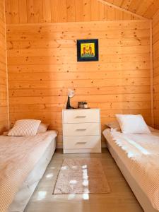 two beds in a room with wooden walls at Domki nad Firlejem in Firlej +7 photos