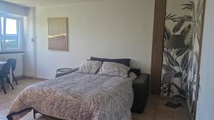a bedroom with a bed and a chair and a table at Prenepla in Ornex