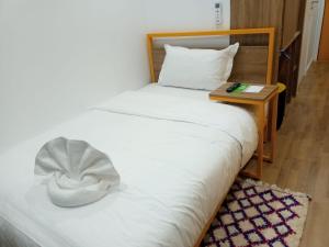 a bedroom with a white bed with a night stand at Oxygen Village in Zeïda