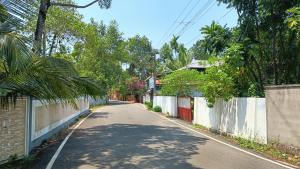 an empty street with a fence and a house at Leland Homestay in Mararikulam