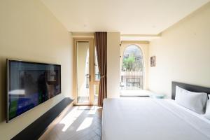 a bedroom with a large white bed and a tv at Weal Apartment in Danang