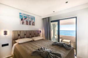 a bedroom with a bed with a view of the ocean at Black Rocks Family Beach Resort in Agios Gordios