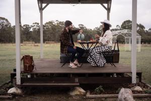 a man and a woman sitting at a table on a deck at Odyssean Tiny House B by Tiny Away in Cessnock