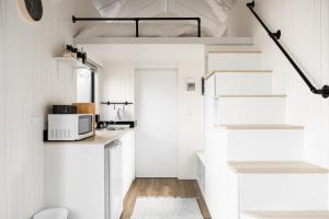a small kitchen with white cabinets and a microwave at Odyssean Tiny House B by Tiny Away in Cessnock +36 photos