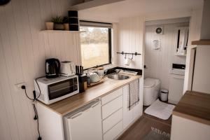 a small kitchen with a microwave and a sink at Odyssean Tiny House B by Tiny Away in Cessnock
