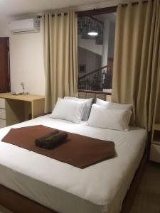 a large white bed with a brown blanket on it at The Cibulan Residence in Jakarta