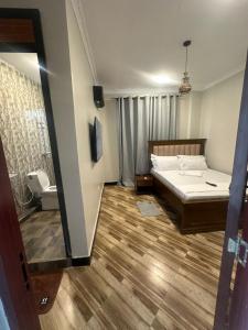 a bedroom with a bed and wooden floors and a mirror at Gekamo Suites in Dar es Salaam