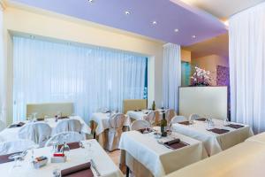 a restaurant with white tables and chairs and a screen at Hotel De Londres in Riccione