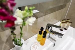 a bathroom sink with two bottles of soap and flowers at Best Western Plus The Met Tirana Hotel in Tirana +52 photos