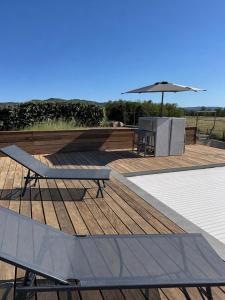 a wooden deck with a bench and an umbrella at Mini Villa avec piscine privée in Porto-Vecchio