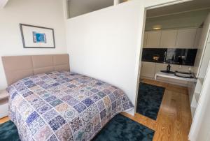 ポルトにあるHome At Porto - Aliados Apartmentsの小さなベッドルーム(ベッド1台付)、キッチンが備わります。
