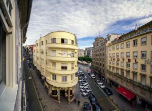 un grand bâtiment jaune dans une ville avec des voitures garées dans l'établissement Home At Porto - Aliados Apartments, à Porto