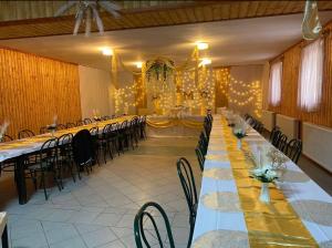 a large banquet hall with long tables and chairs at Horgász-Vadász Vendégház in Egyek