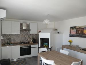 a kitchen with white cabinets and a wooden table at Nel cuore di Segesta in Calatafimi