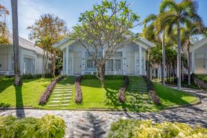 a house with palm trees in front of it at Carmelina Beach Resort Ho Tram in Ho Tram