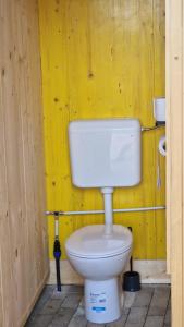 a bathroom with a white toilet in a yellow wall at Camp Starshine near Bled in Begunje na Gorenjskem +24 photos