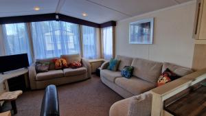 a living room with two couches and a television at Oystercatcher Hide, Chruch Farm in Pagham