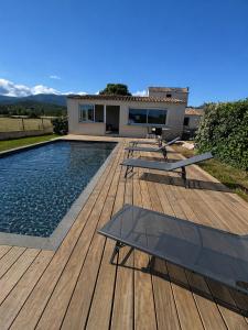 a wooden deck with a swimming pool and a house at Mini Villa avec piscine privée in Porto-Vecchio