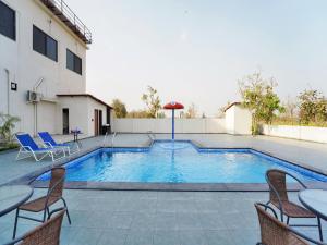 a swimming pool with chairs and a table at Palette Hotel Orient Greenz by CheckIn, Pench in Khawāsa